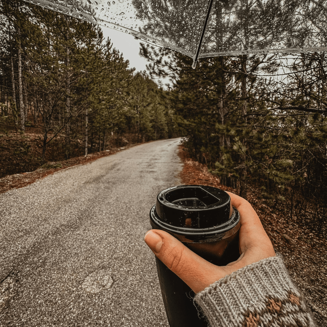 walking in the rain on a trail with a coffee -The Best 60 Slow Living Quotes for a Peaceful Lifestyle