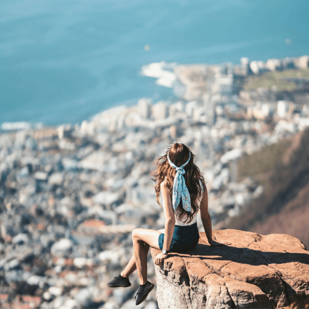 girl sitting on the edge at the top of a mountain