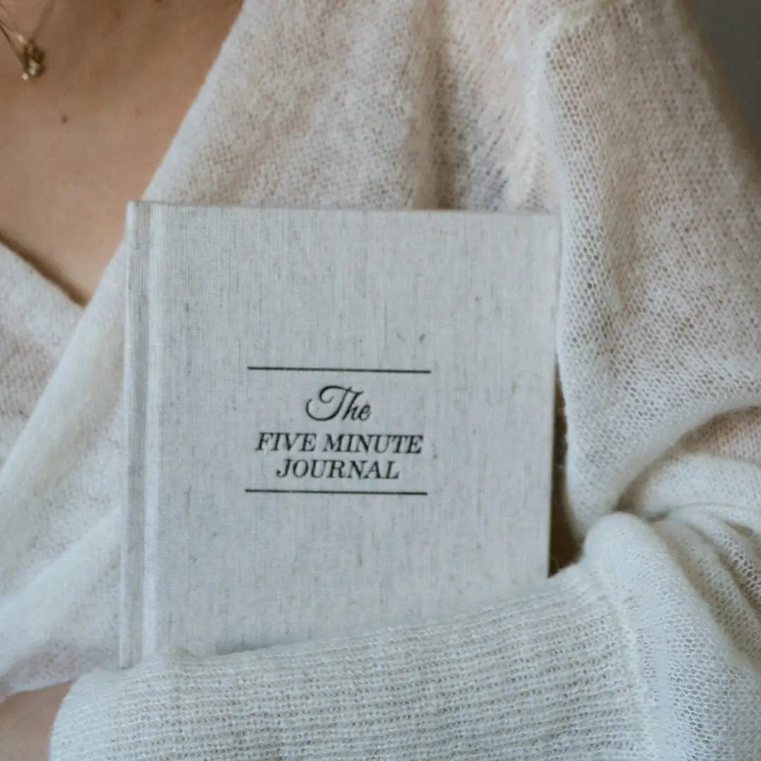 A Person Wearing White Cardigan Holding a Journal -50 Powerful Journaling Prompts to Overcome and Save You From Your Self-Sabotaging Behaviour