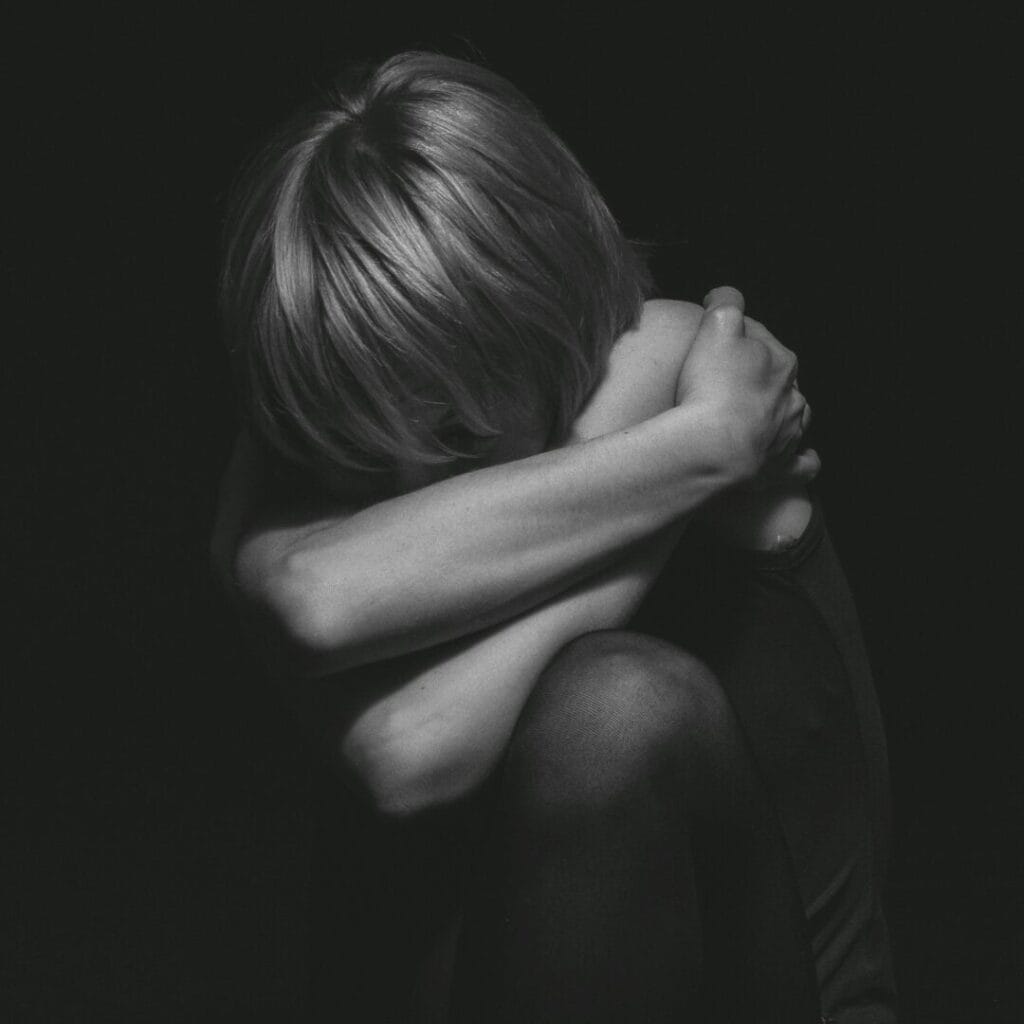 Grayscale Photo of a Person Hugging Self- portrayal of self sabotage-showing Emotional Withdrawal, Self-Protection, Isolation and Fear, Internal Conflict